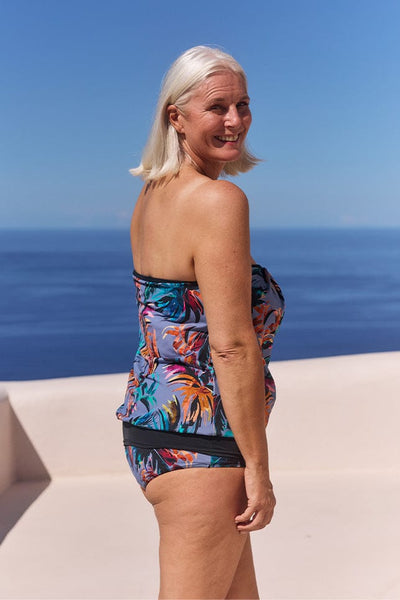 Side profile of model wearing flouncy bandeau tankini top with removable and adjustable straps