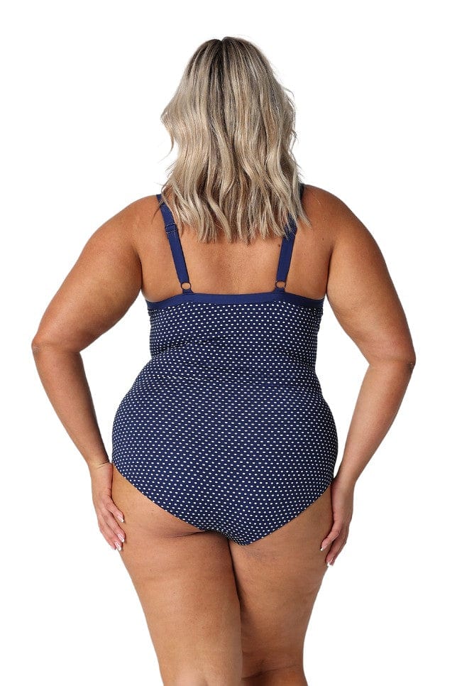 Blonde model in studio wearing plus size underwire one piece in polkadot navy with adjustable straps