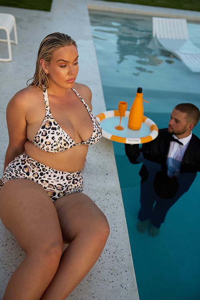 Model wearing snow leopard triangle bikini sitting next to pool