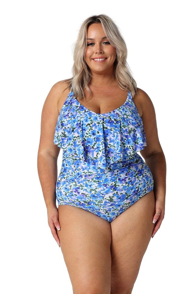 Blonde model in studio wearing curvy white and blue floral swimsuit with frill v neck