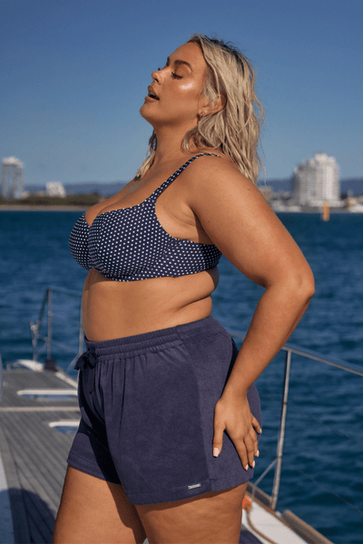 Side profile of blonde model on boat wearing flattering plus size beach short in terry towelling