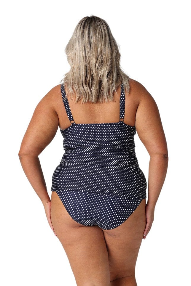 Back of model in studio wearing navy and white dots tankini top with adjustable straps
