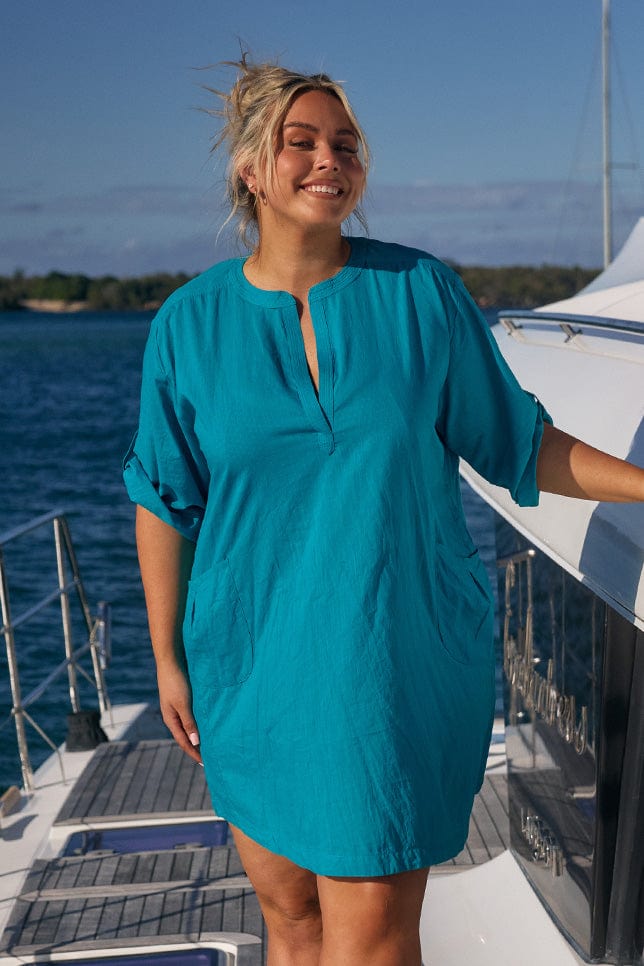 Blonde model wearing ocean coloured beach dress on boat