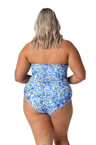 Back of plus size model in studio wearing blue and white floral one piece with removable straps