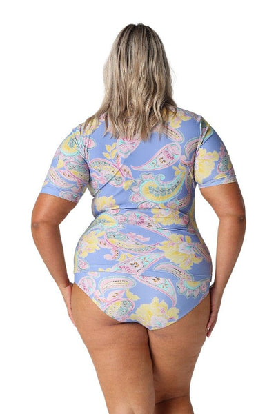 Back photo of model in studio wearing a pastel coloured rash vest with paisley print