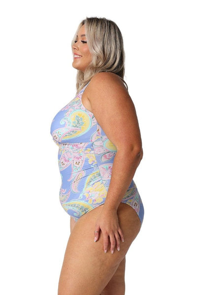 Side profile of curvy woman wearing a flattering blue paisley swimsuit with high neck