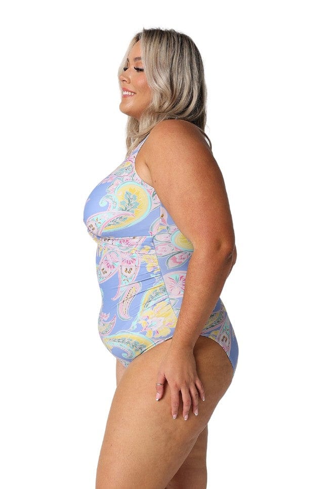 Side profile of curvy woman wearing a flattering blue paisley swimsuit with high neck