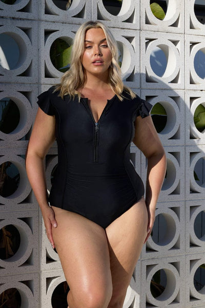 Blonde model wearing black frill sleeve zip up one piece swimsuit