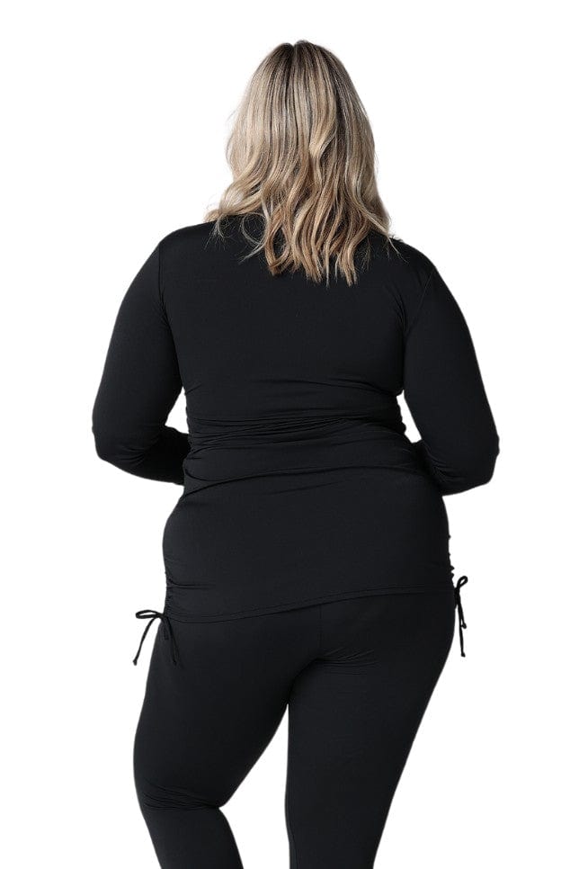 Back of model wearing plus size swim shirt with long sleeves with ruching detail on side in chlorine resistant