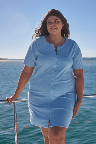 Front of model on boat wearing flattering plus size women beach dress with flattering neckline in terry towelling