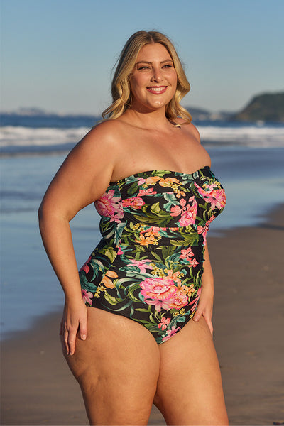 Model showing side of black floral strapless one piece at beach