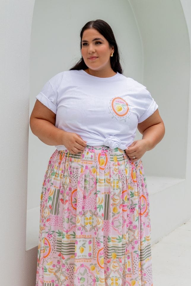 Brunette model wearing loose white t shirt with tutti frutti print for curve women