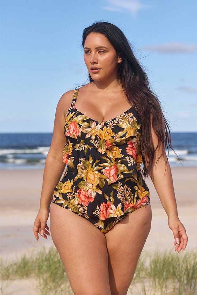 model wearing black and gold floral 3 tier one piece on beach