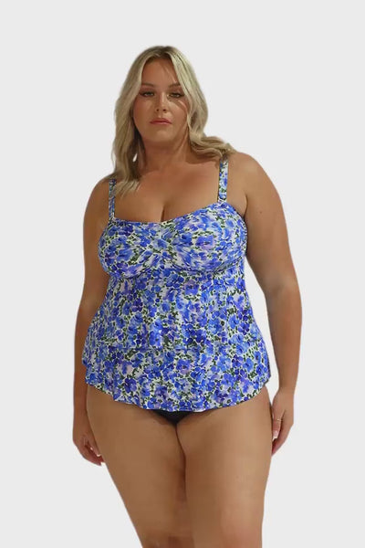 Plus size model in the studio wearing a blue and white tankini with ruffles and removable straps