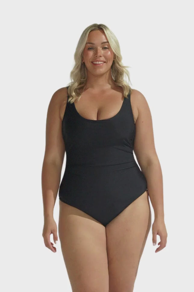 Blonde model wearing black scooped one piece swimsuit