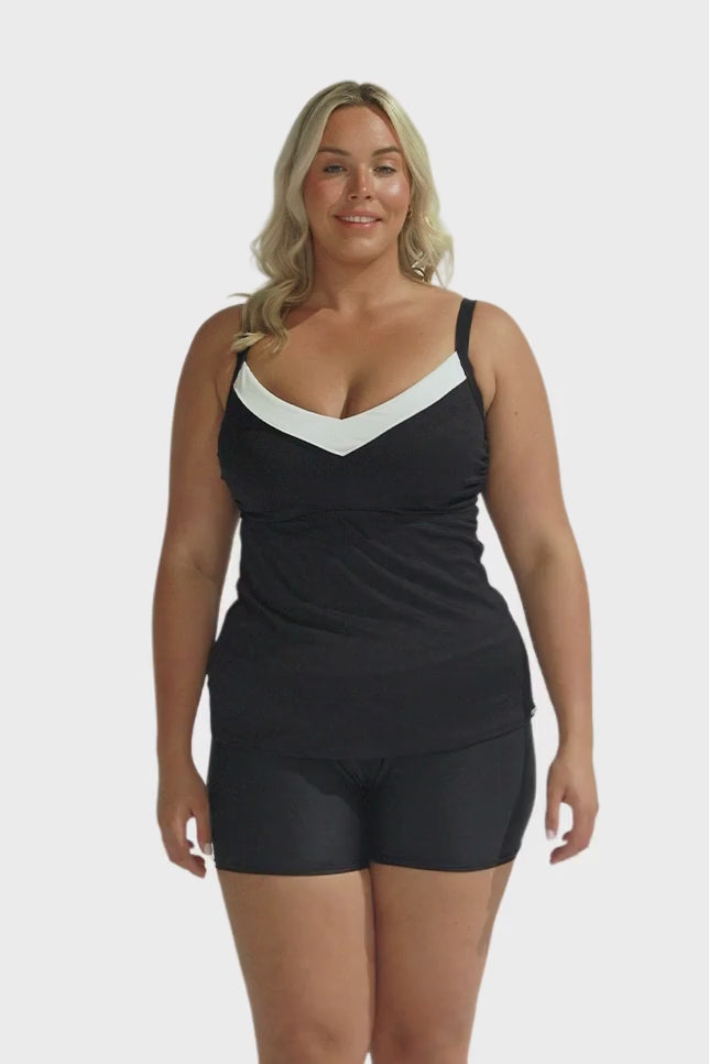 Blonde model wearing black and white underwire tankini with black swim shorts